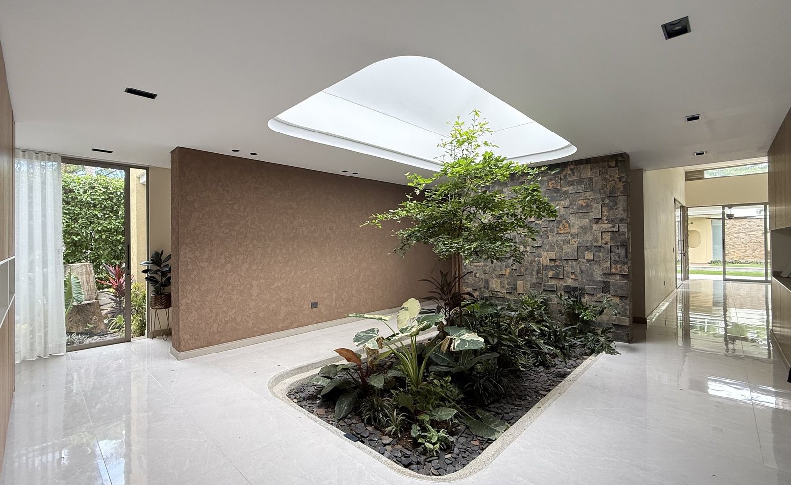 Patio interior con claraboya y árbol, proyecto AMAD Architectural Design